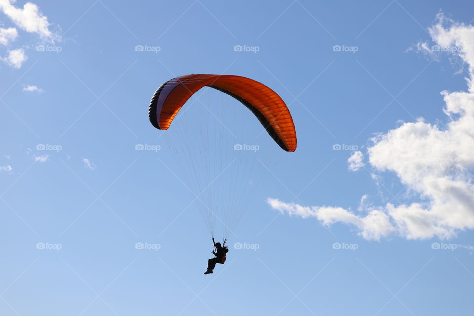 Paraglider up in the air against blue sky