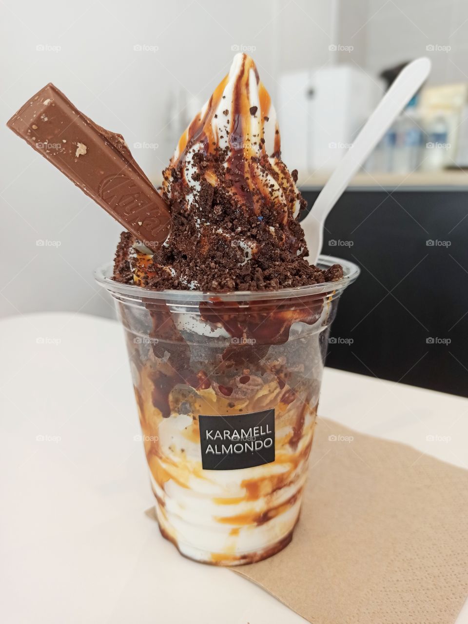 Yogurt Ice cream coated with Caramel, chocolate rice and chocolate cookies served in a plastic cup.