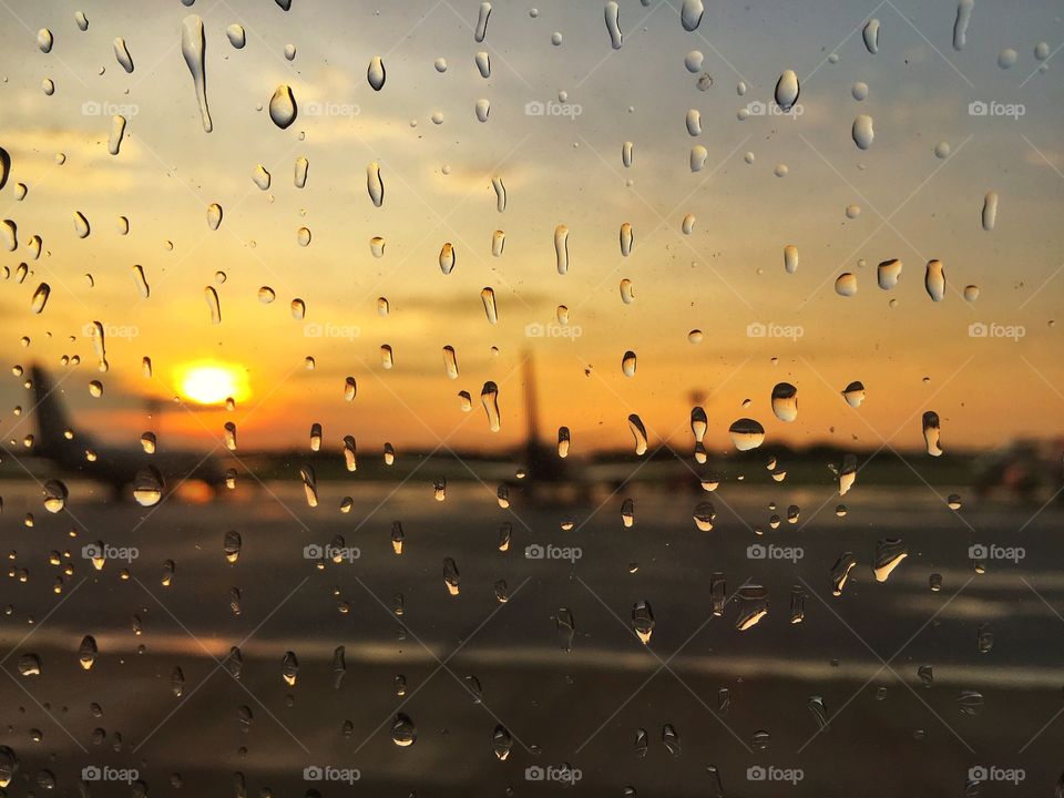 Many raindrop on airplane window with blur airport background