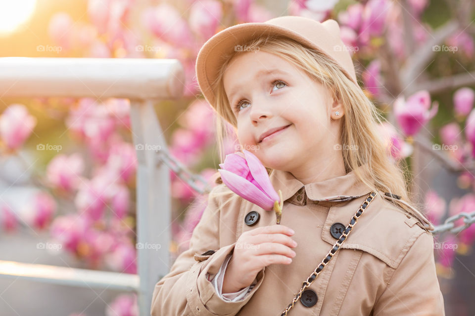 Portrait of cute little girl with blonde hair and magnolia flower