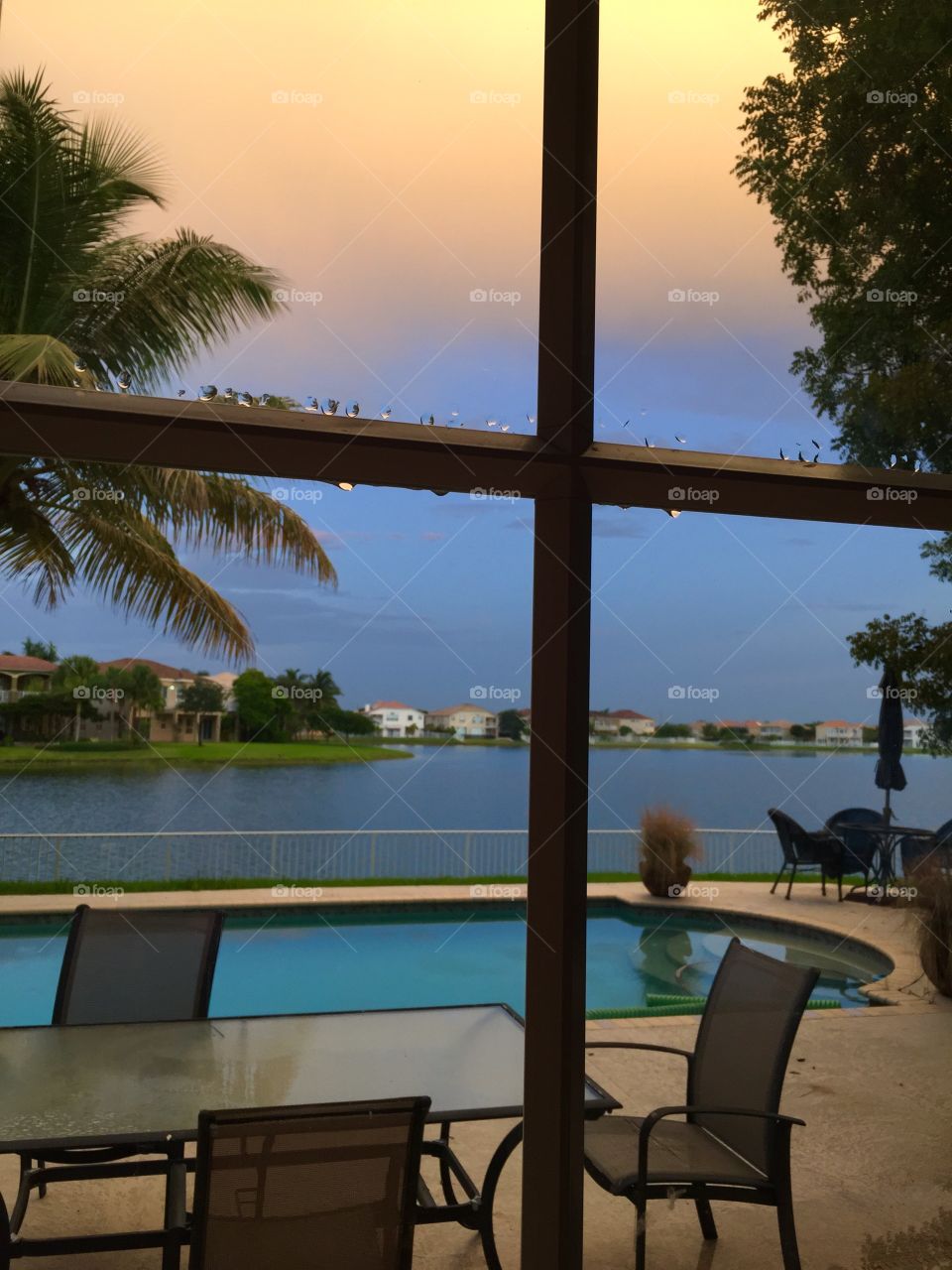 View through a window. View of pool and lake through a window at sunset after a storm 