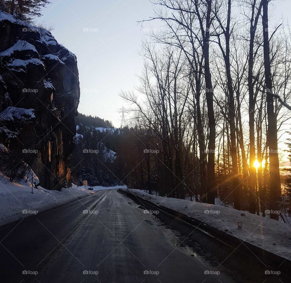 Sunset on icy road with snowy boulder overhang
