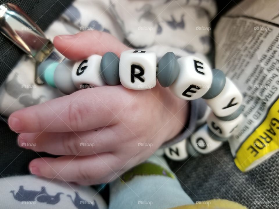My son holding his pacifier clip.