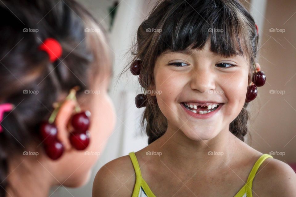 Happy cute girl with cherries and her reflection