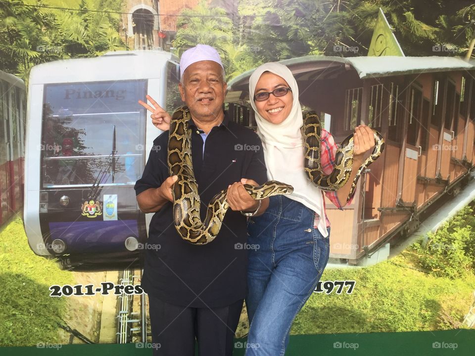 Portrait of father and daughter holding snake