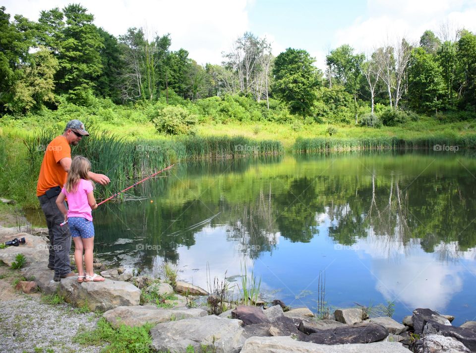 Father and daughter fishing at a pond 