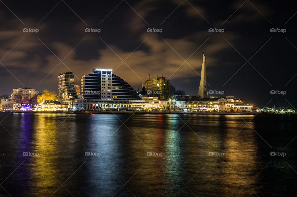 cityscape of a night city with reflection of city lights in sea water