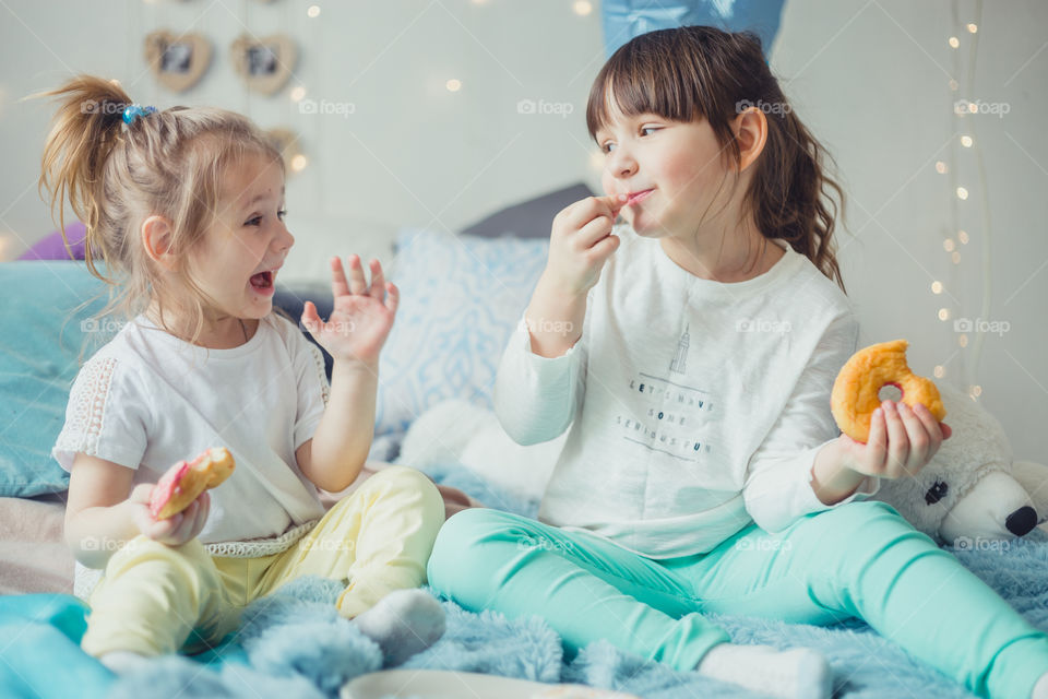 Little sisters eating donuts 