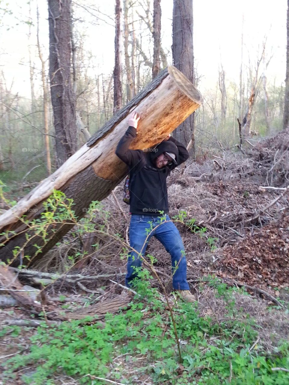 Young man carrying log in forest