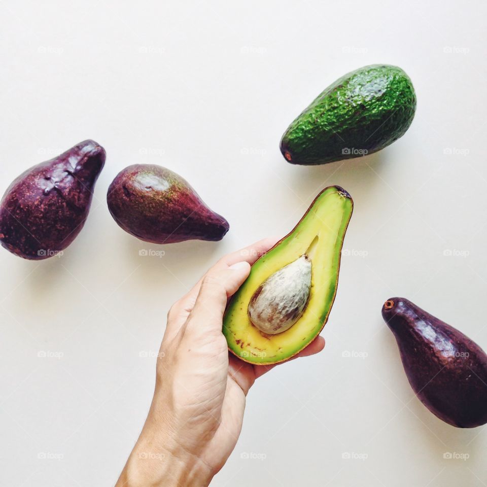 A person holding avocados