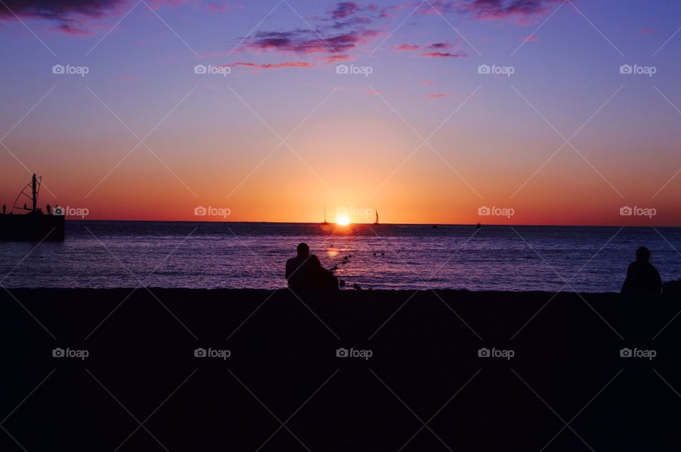 A couple watching sunset at the beach. 