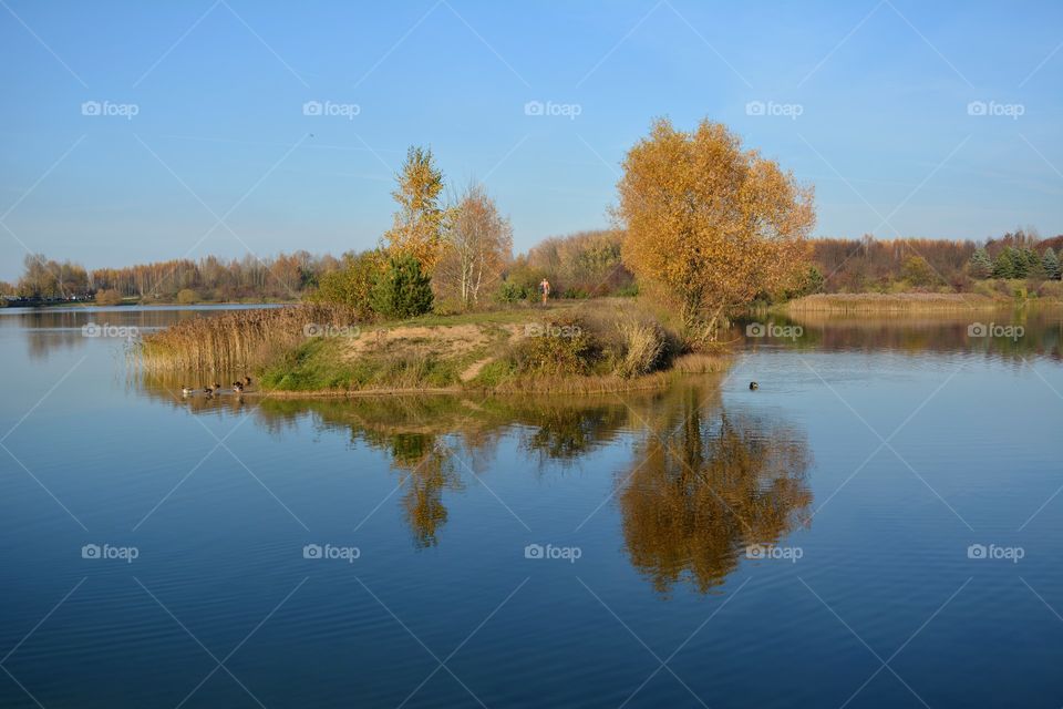 beautiful autumn landscape lake shore and person walk blue sky background