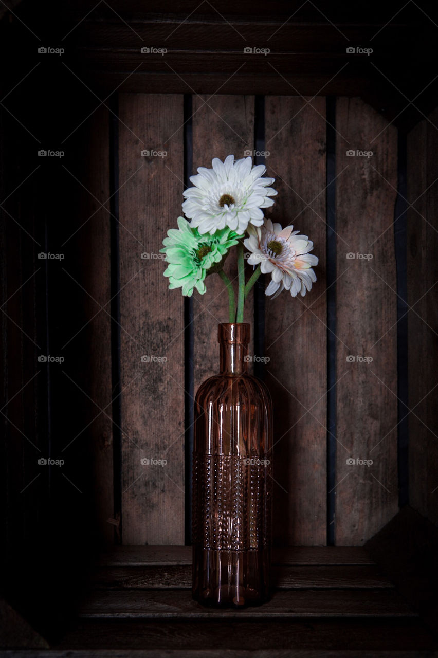 Flowers in a vase in a dark crate