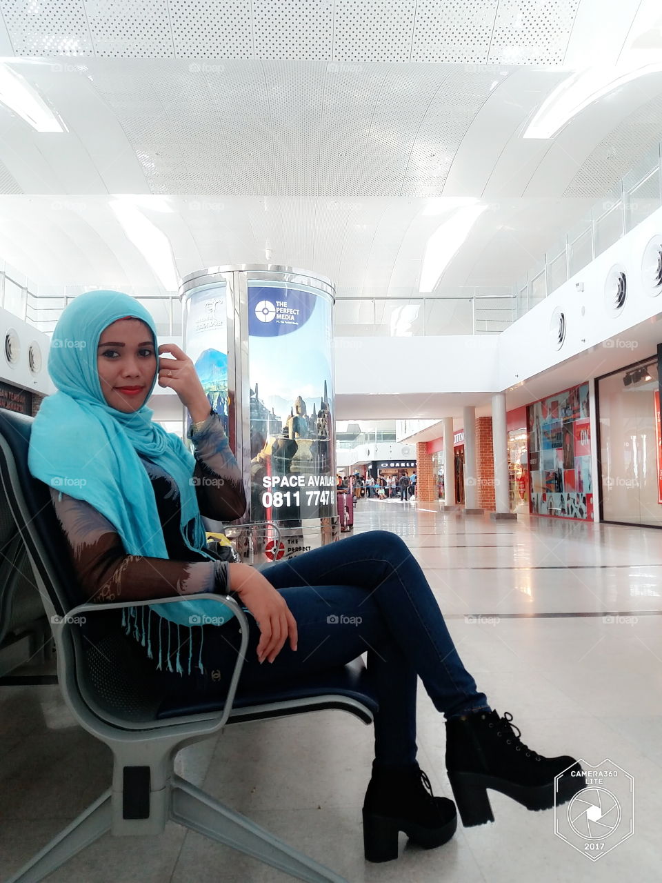 Young woman in hijab sitting on bench at shopping mall