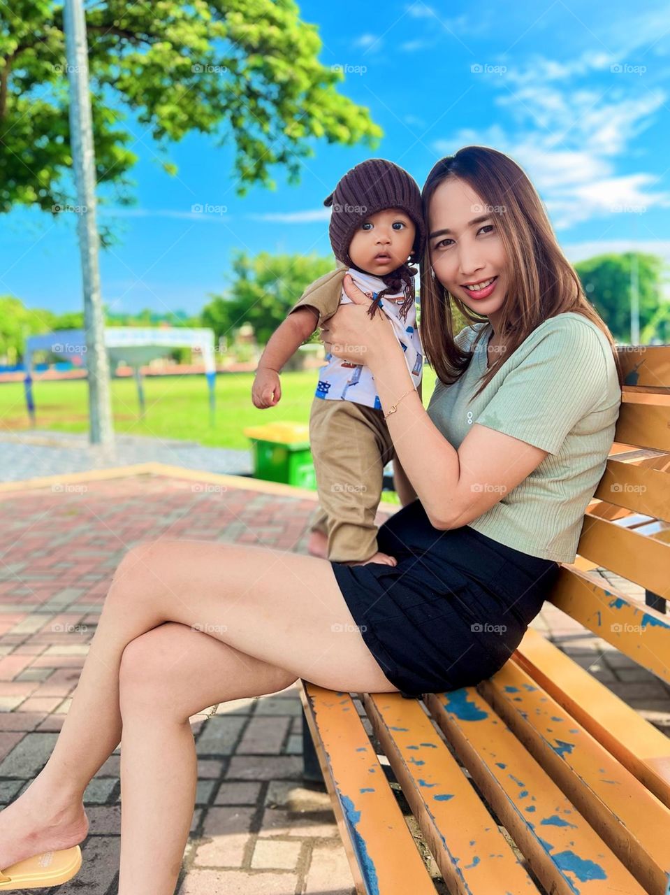 Portrait of a young mother holding her son on a park bench