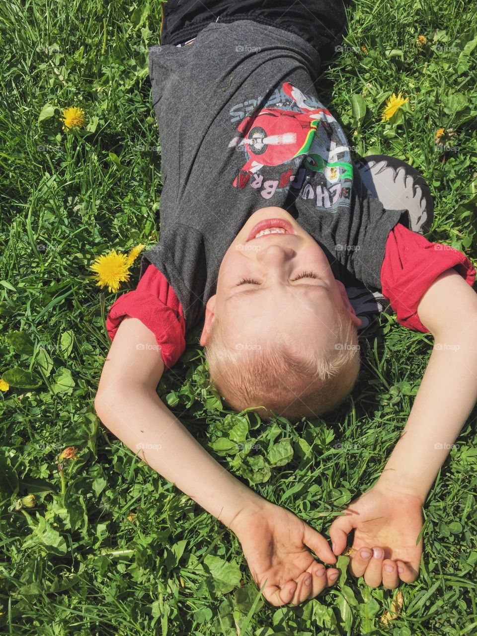 Boy laying in the grass with a happy face