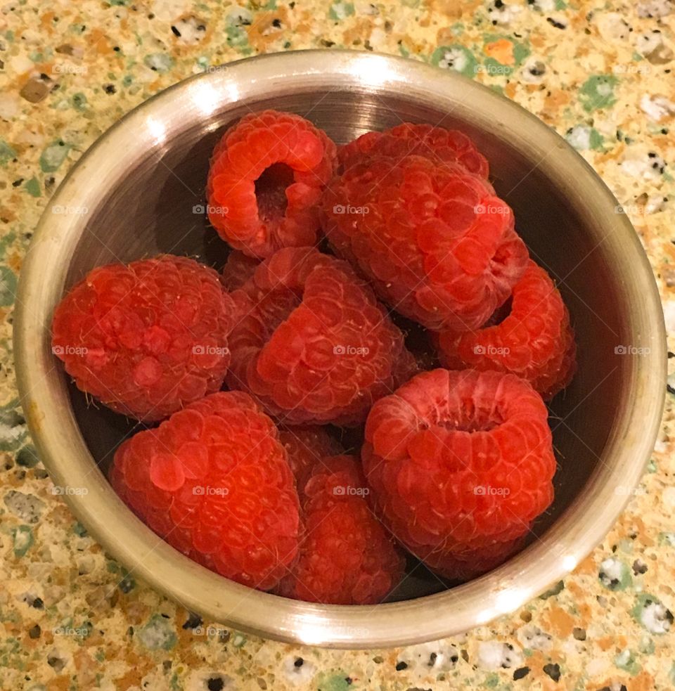 Closeup of Red raspberries in a small stainless steel bowl 