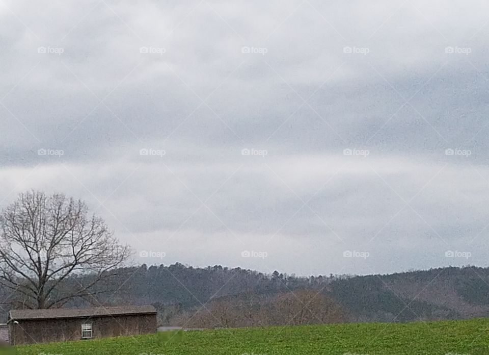 small barn, on grassy ground, across from mountain