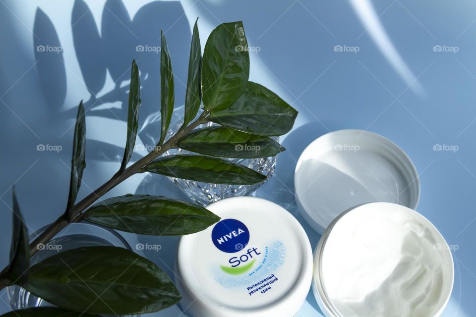 Nivea skin care product on a blue background with a green flower.