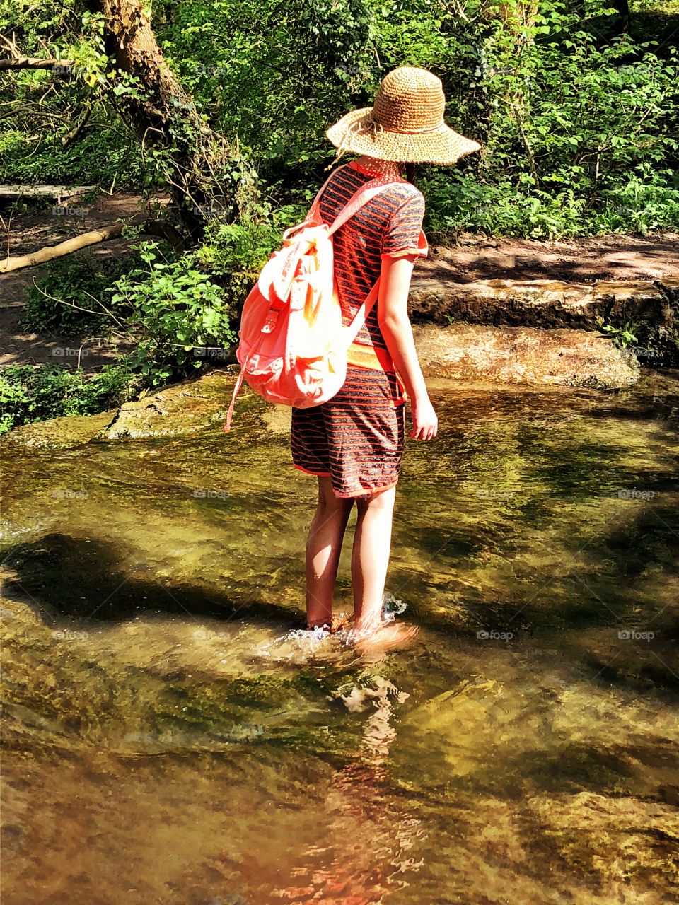 Girl enjoying the summer sunshine. Paddling barefoot in a woodland river. The best things in life are free.