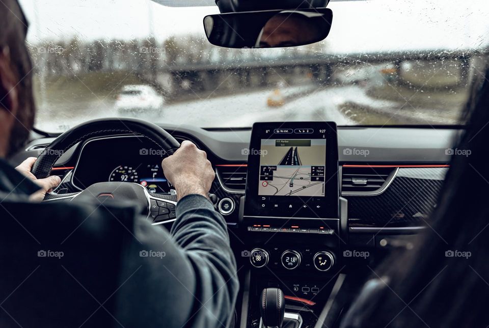 Rear view of a man driving modern car on highway on a rainy day