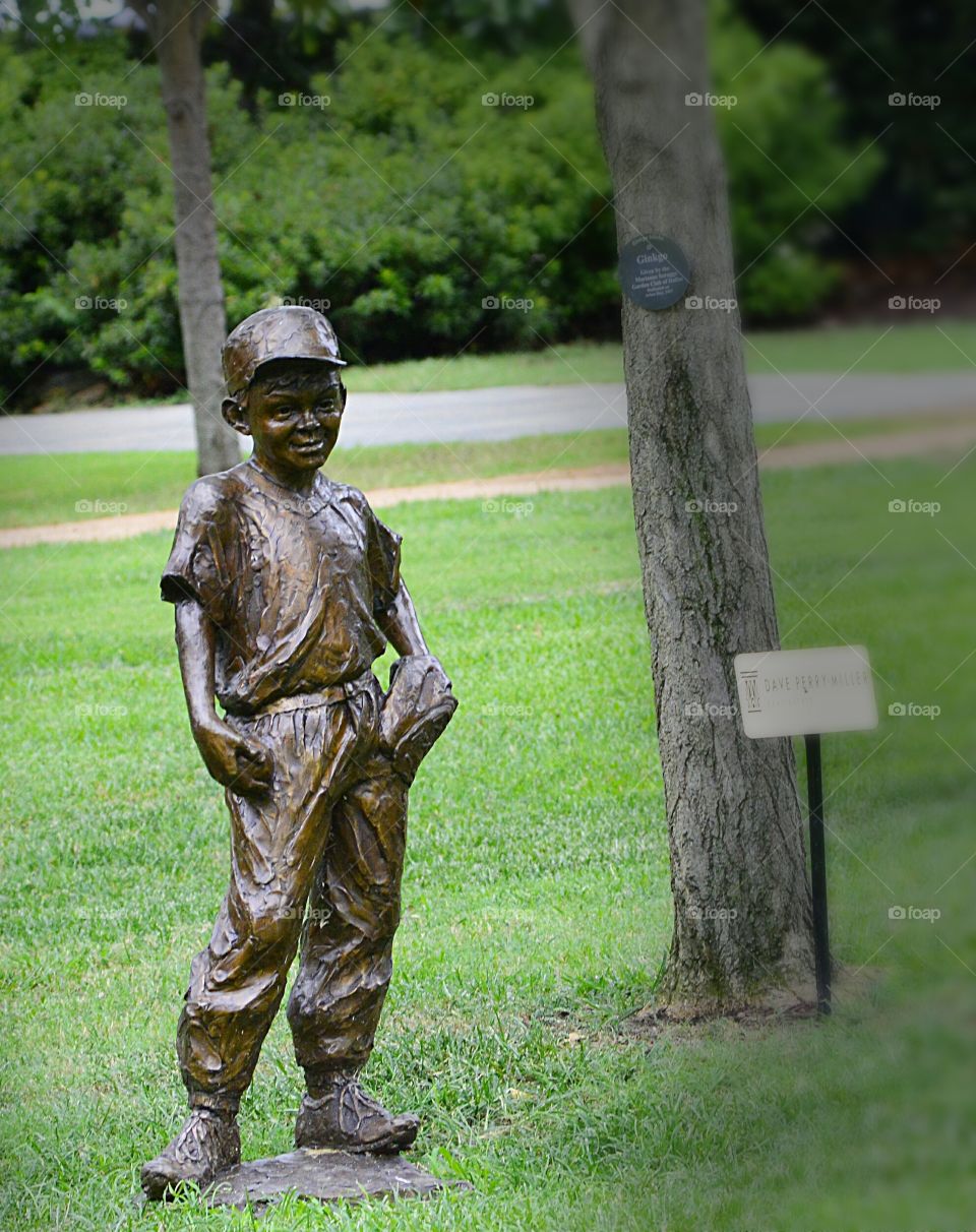 Mischief in every Game: The bronzed baseball kid looks perfect posed in a park, but catch the shadow just right, and a mischievous little boy comes to play.