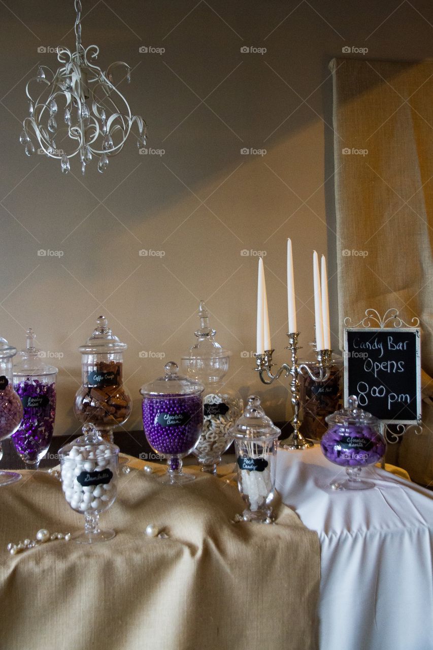 Candy bar at a reception with purple themed candies in glass jars