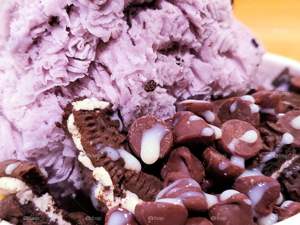 close up of delicious taro shaved ice dessert with chocolate chips,  oreo cookies and drizzled sweet condensed milk.