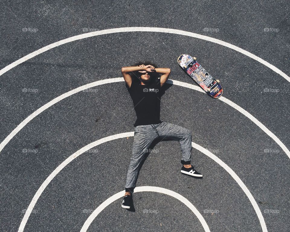 Elevated view of a man lying on asphalt with skateboard