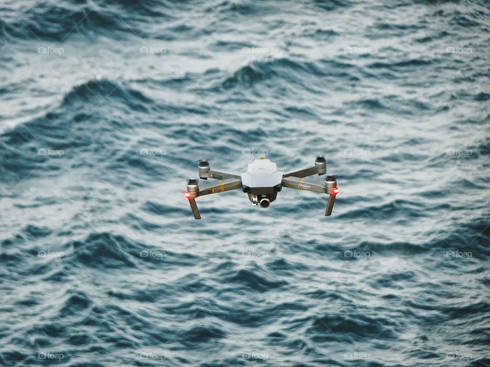 Beware, this drone is looking at you! Drone flying high above the stormy dark sea. 