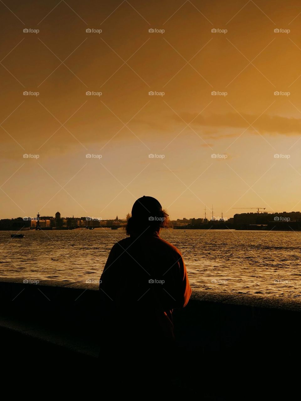 Unrecognisable male standing on the pier and looking of beautiful sunset in summer day, back view 