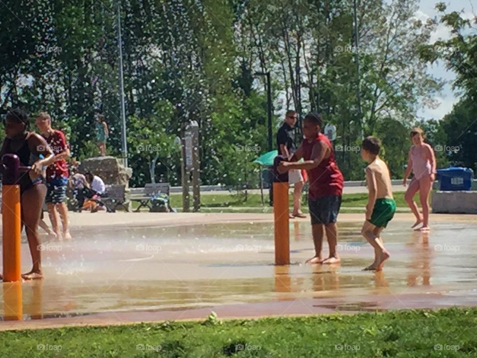 Kids playing at a splash pad during summer in the city.