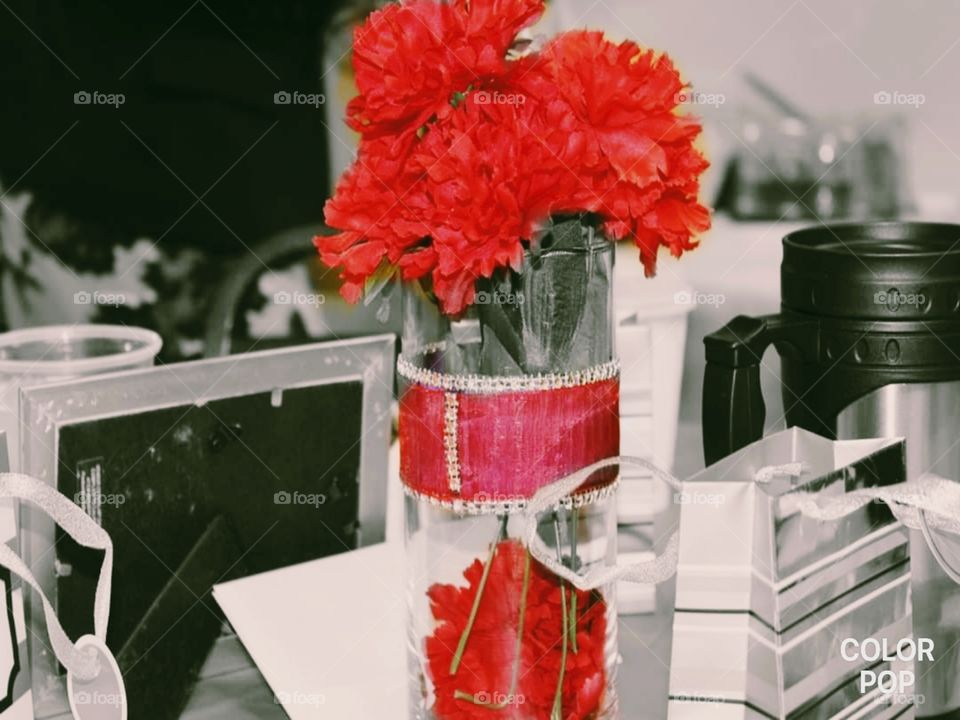 Ravaging red flowers in a clear case with a red sash accented with rhinestones