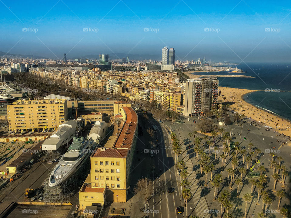 Barcelona view of port and beach from Telefèric de Port. A long view of the coastline containing buildings, beaches, parks and boats