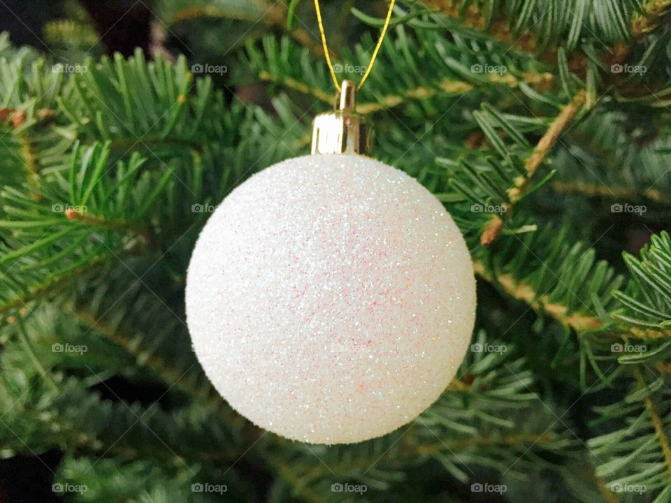 White glittering Christmas globe hanging in the Christmas tree