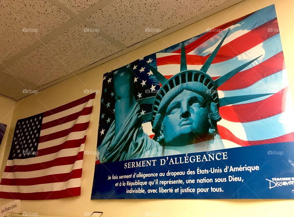 Pledge of Allegiance in French and an American flag on classroom wall