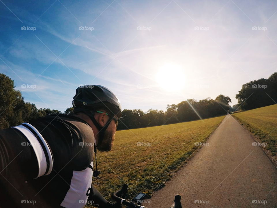 towards the sun. roadbike ride in the morning. with helmet and bike clothes.