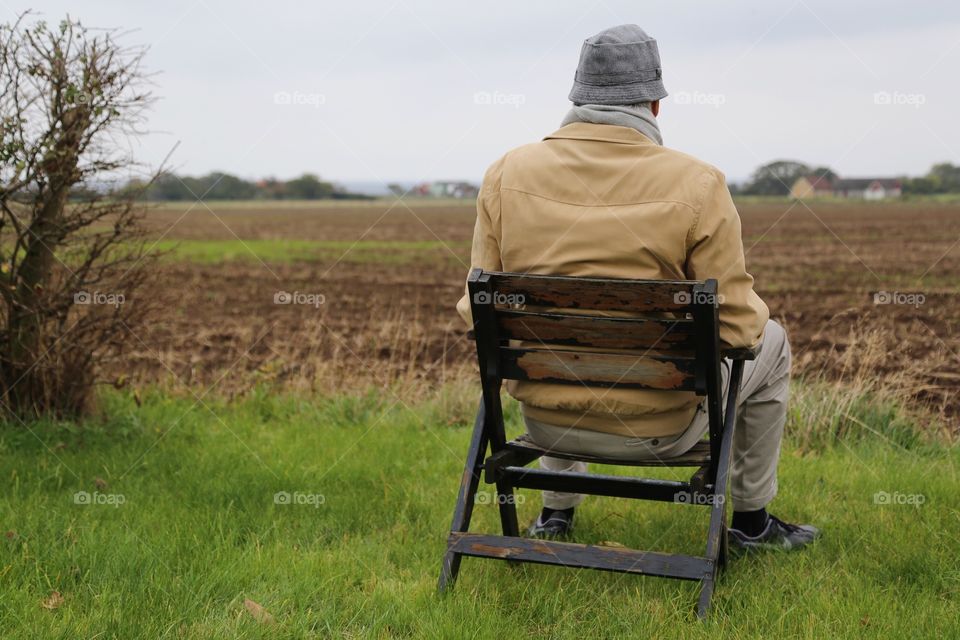 Man from behind sitting outdoors watching the field 