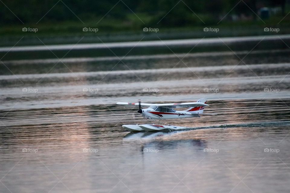 Toy airplane lands on water during sunset