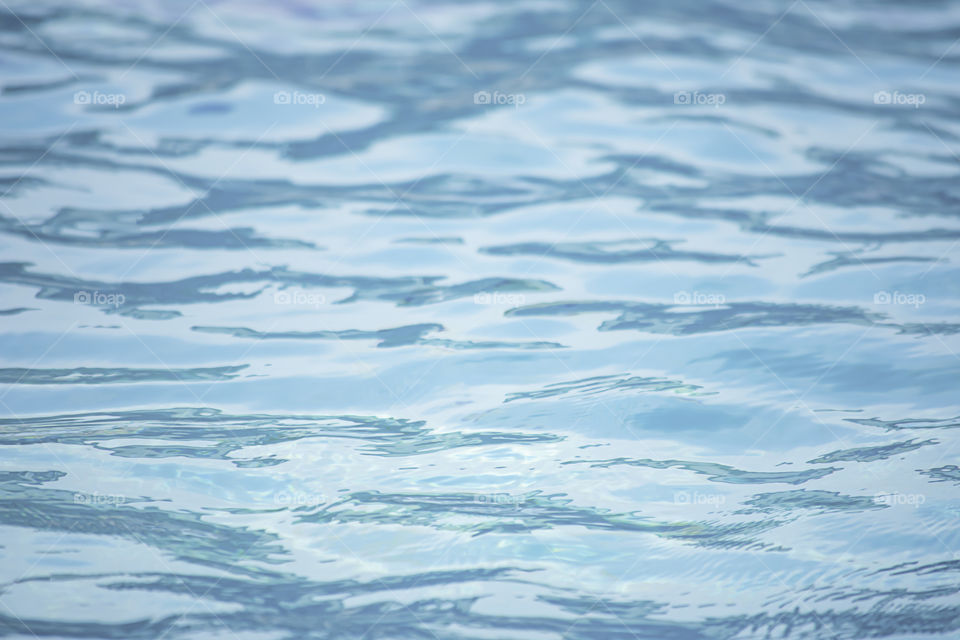 The blue water waves by wind and sunlight reflecting surface