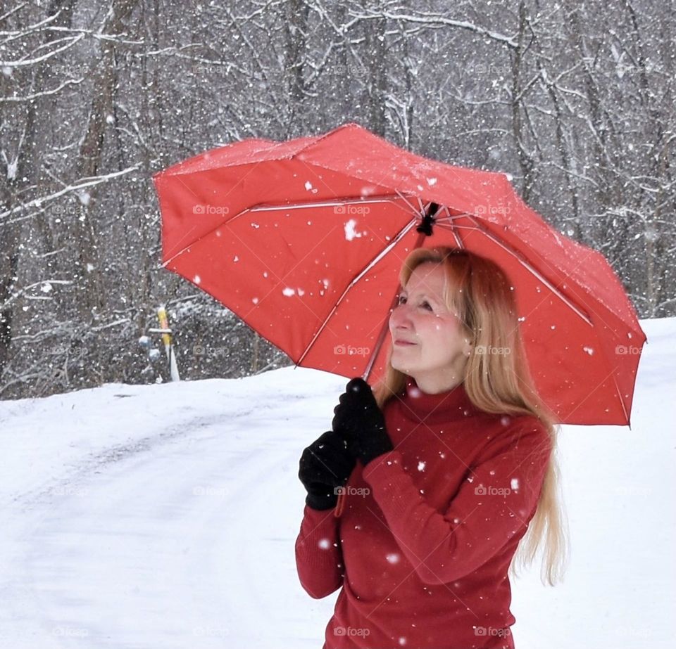Woman in red sweater with red umbrella in the snow