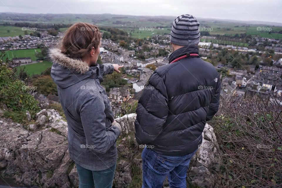 Young couple admiring the view of Settle in Yorkshire.. high up on a hillside ...