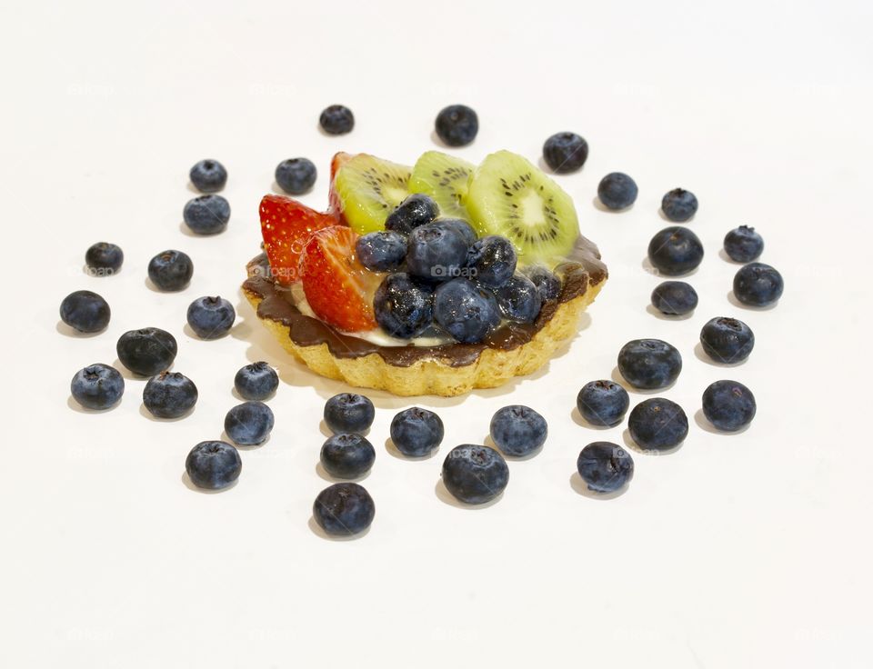 Fruit tart surrounded by a pattern of blueberries 