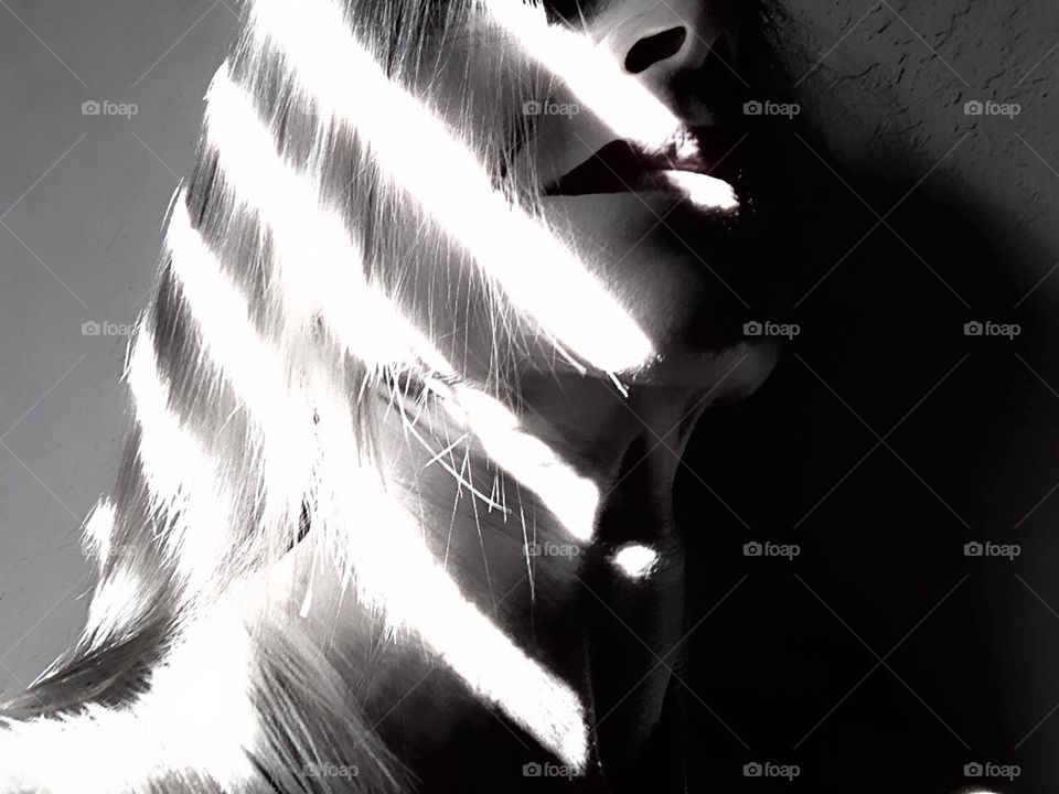 Light and shadows leave an alternating pattern on a woman’s profile.