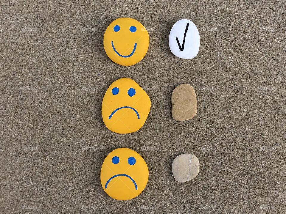 Check mark in a check box, positive customer experience, conceptual stones composition over beach sand