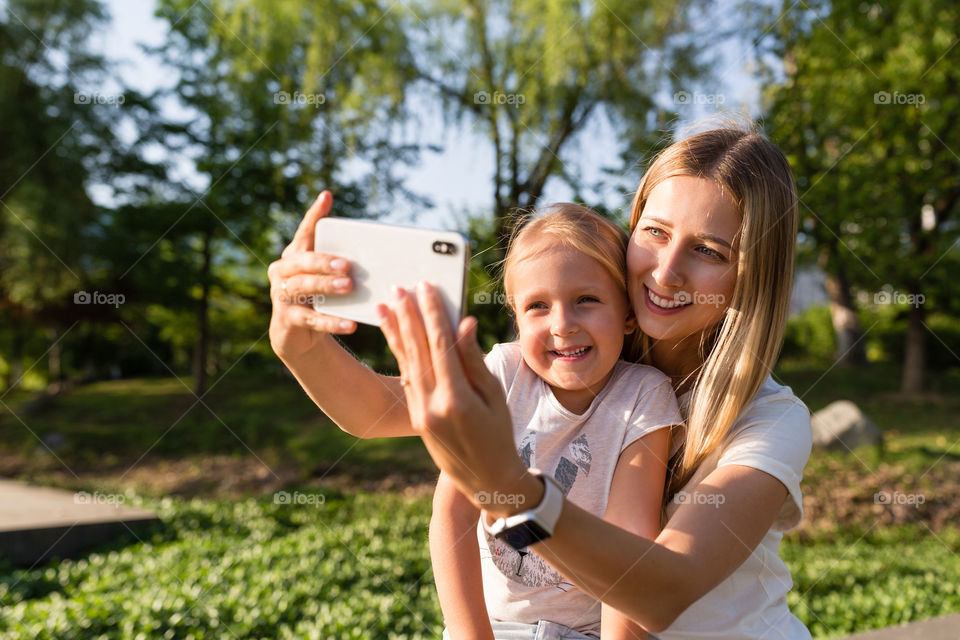 Mother and daughter making selfie outdoor 