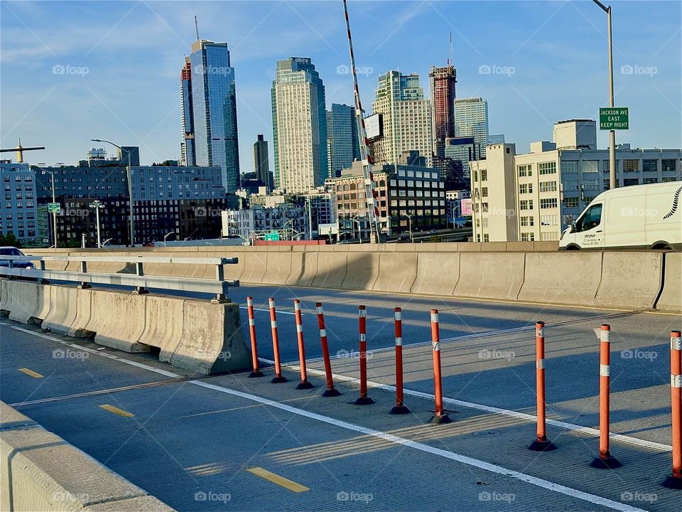 This is the „Pulaski Bridge“ at „Newtown Creek“ that connects „Greenpoint“, Bklyn to LIC, Queens in the direction we are currently heading. Up ahead we see nearby LIC high rises all aglow in the evening sun. 2024. Hypnotic Productions