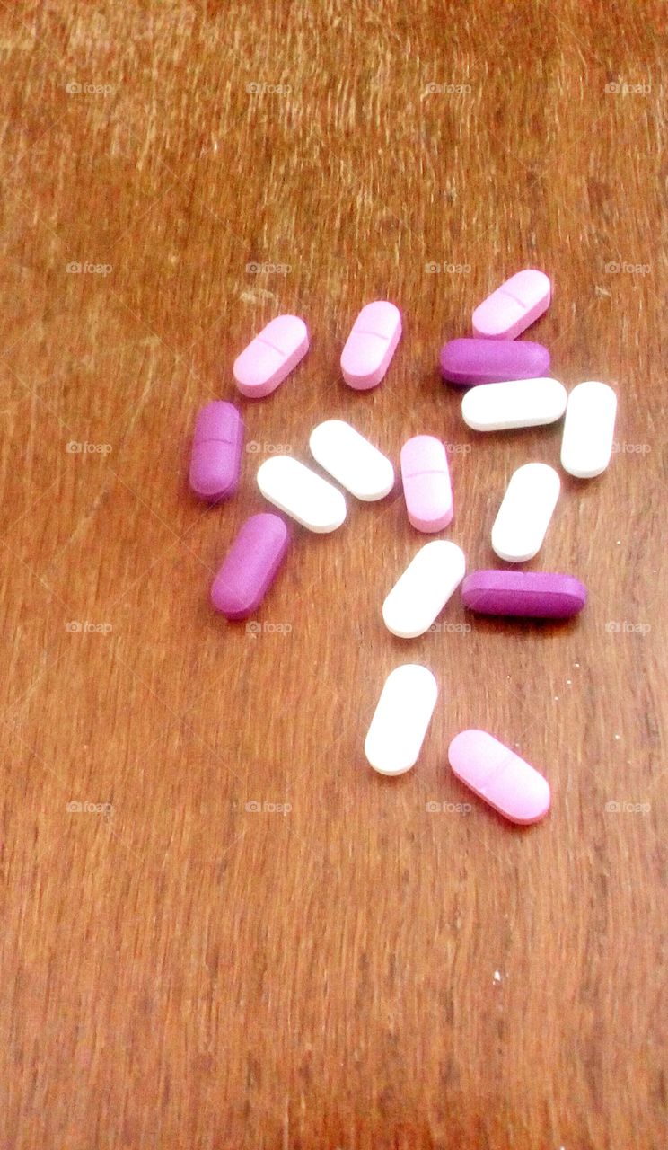 Group of colorful pills on wooden table