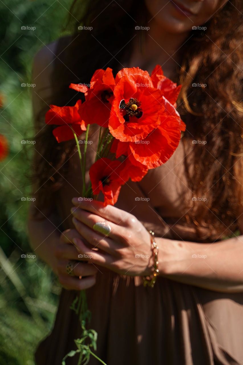 A bouquet of poppies in the hands of a girl