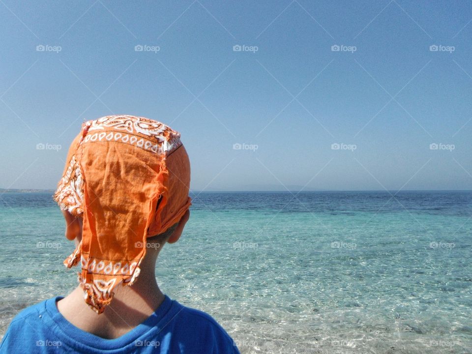 orange bandana in front of blue sea